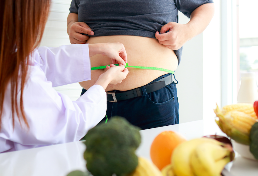 Bariatric surgeon taking waist measurement of obese person
