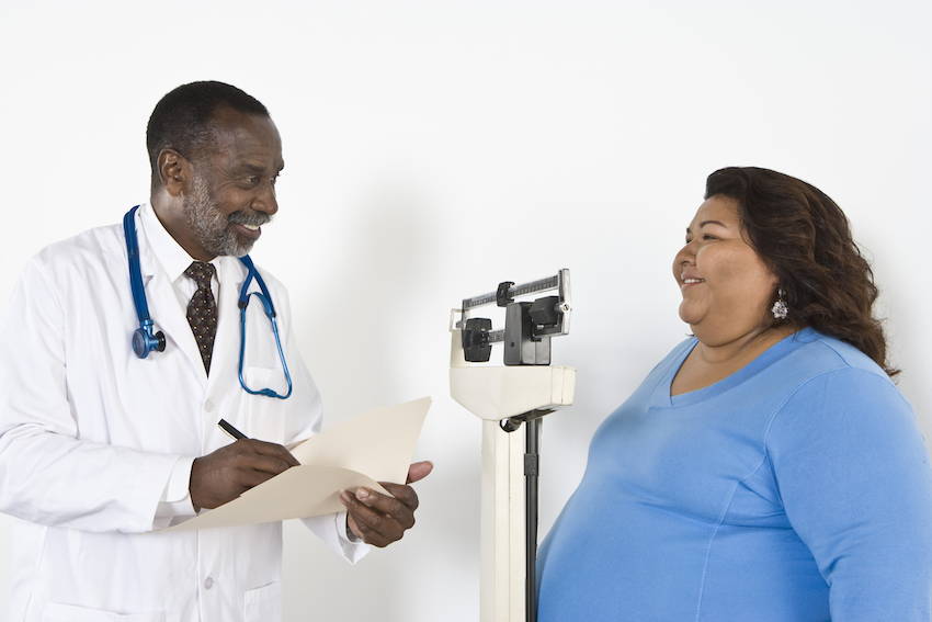 Woman with obesity being weighed at doctor’s office
